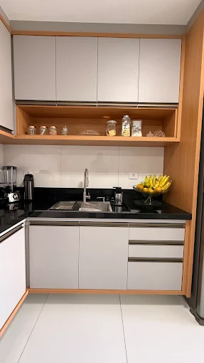 Cozinha compacta planejada com armários off-white, nicho em madeira e bancada preta