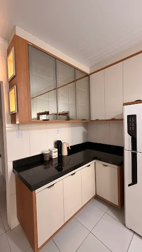 Cozinha planejada com armários de vidro reticulado, bancada preta e detalhes em madeira